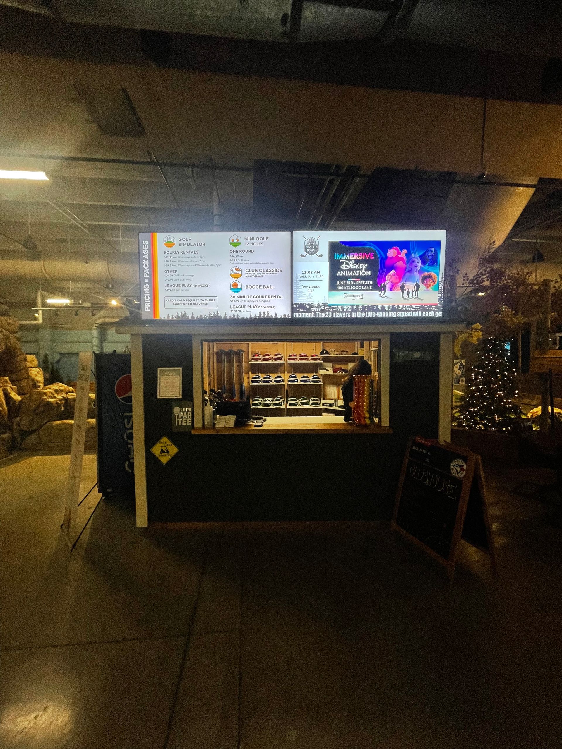Nighttime food kiosk with bright menu boards and a lit counter in a dark outdoor setting