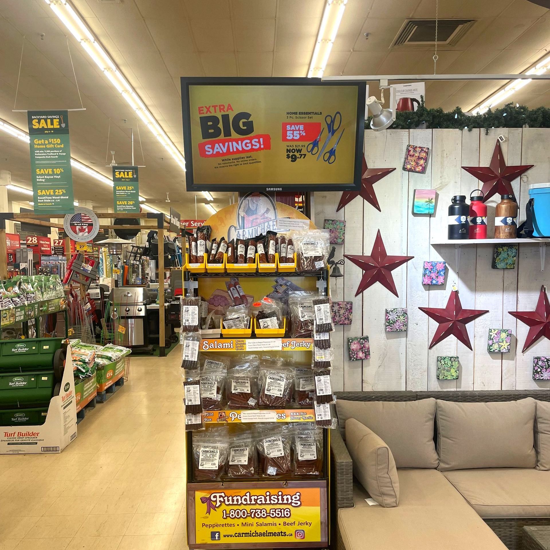 Home Hardware store aisle with holiday decorations, gift items, and sale signs under bright fluorescent lights