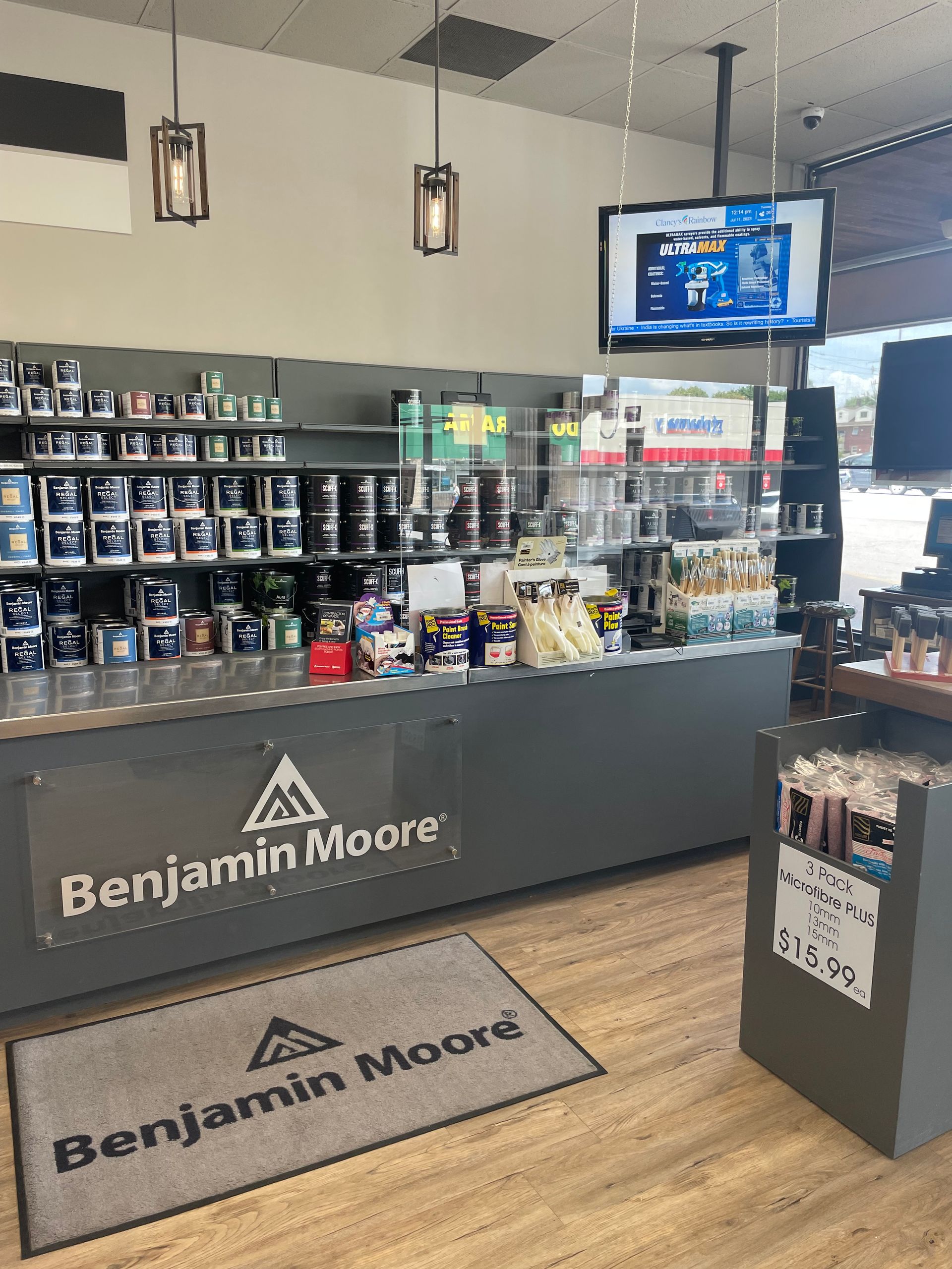 Benjamin Moore paint store interior with product displays, counter, and wall-mounted TV