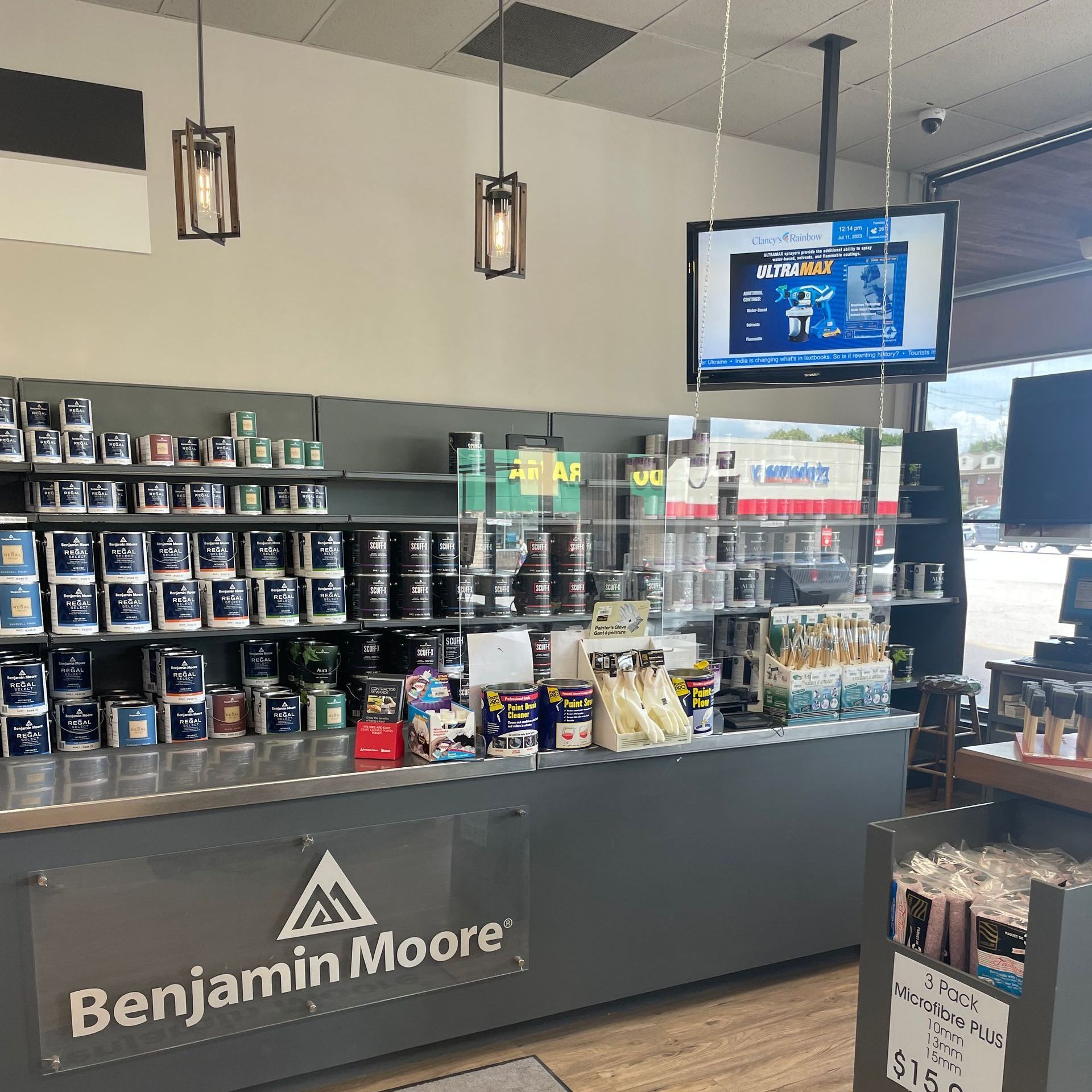 Benjamin Moore paint store counter with shelves of paint cans and a digital display screen