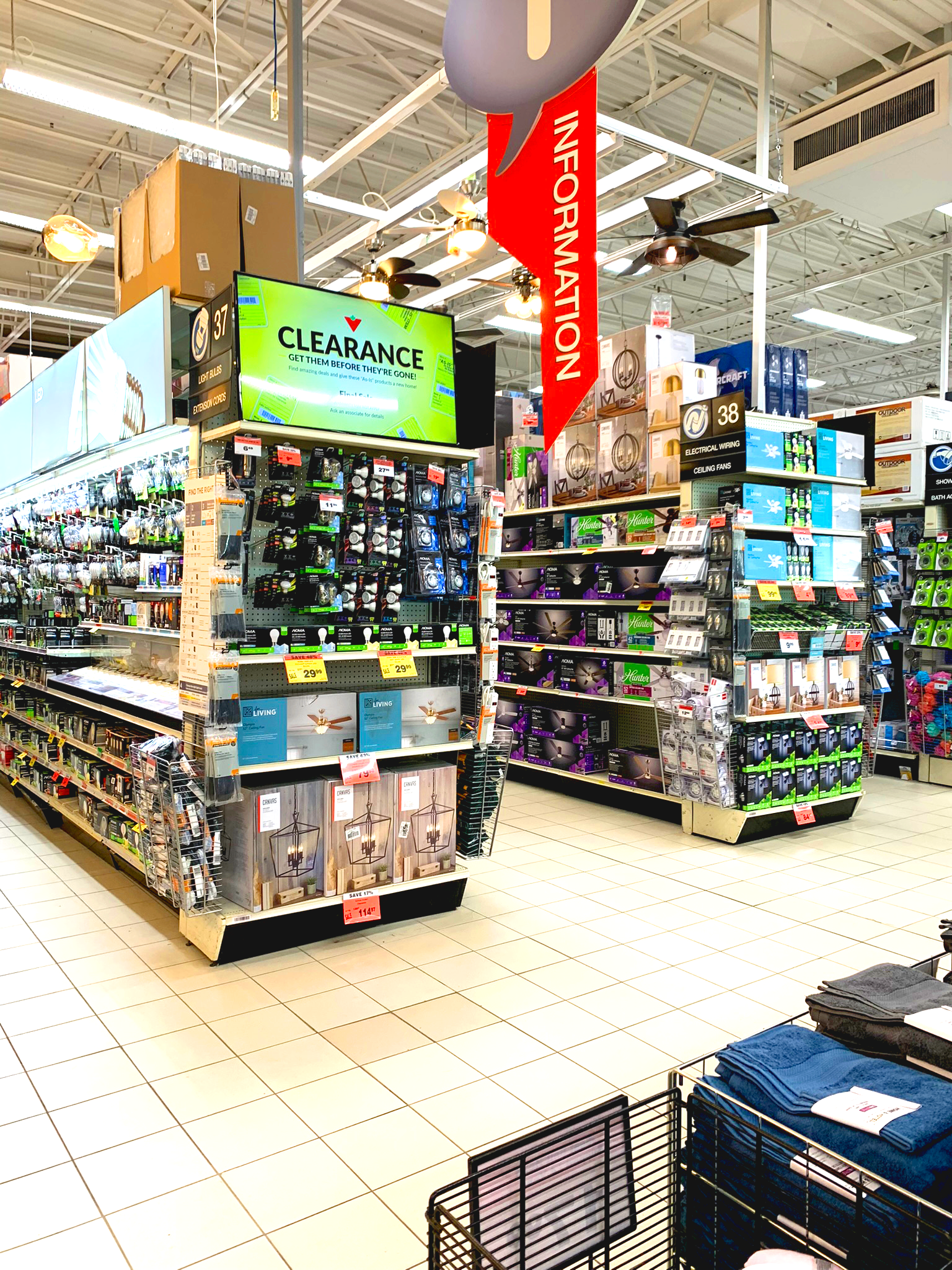 Electronics store aisle with rows of gadgets and colourful digital signage signage in a bright retail setting