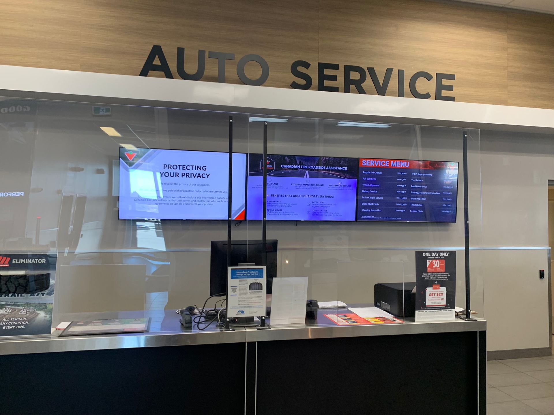 Auto service counter with glass windows, computer screens, and a black counter under an “AUTO SERVICE” sign