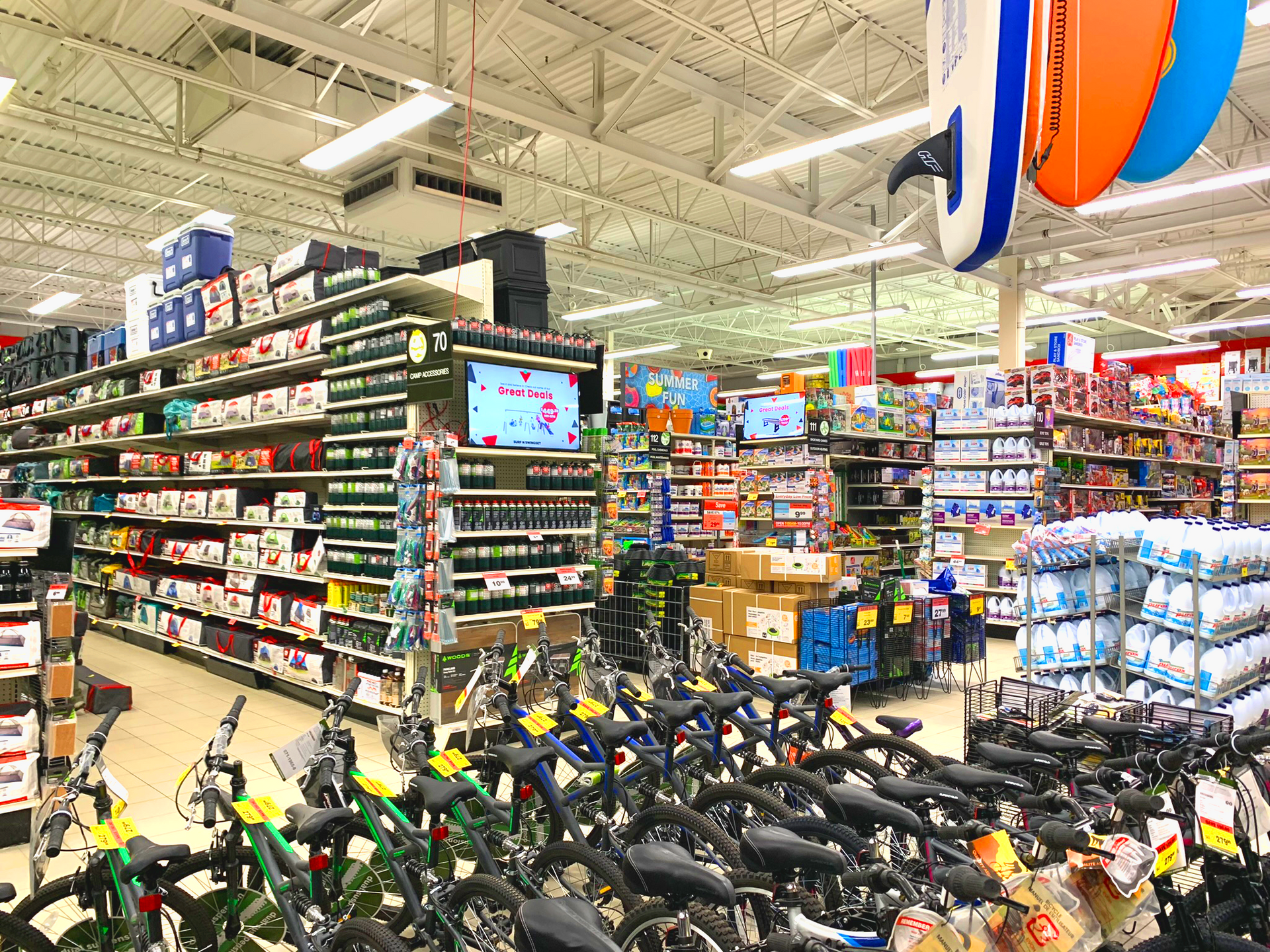 Canadian Tire store aisle with rows of bicycles and shelves stocked with products under fluorescent lights