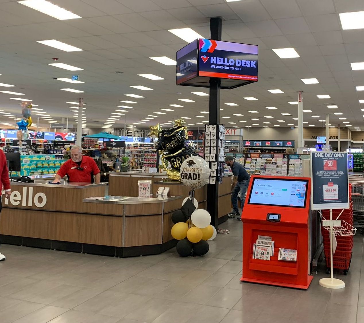 Bright retail store checkout area with a “Hello” sign, balloon display, and red self-service kiosk
