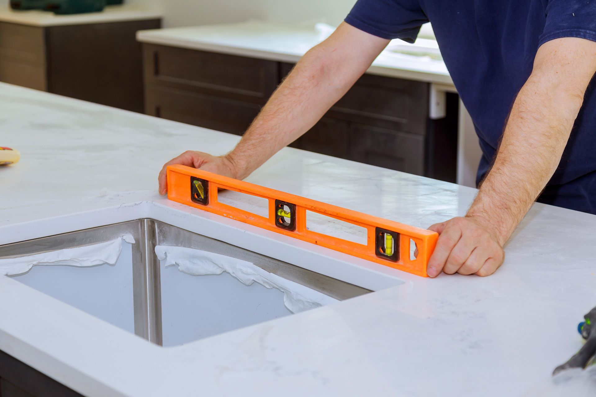 A man is measuring a kitchen sink with a level.