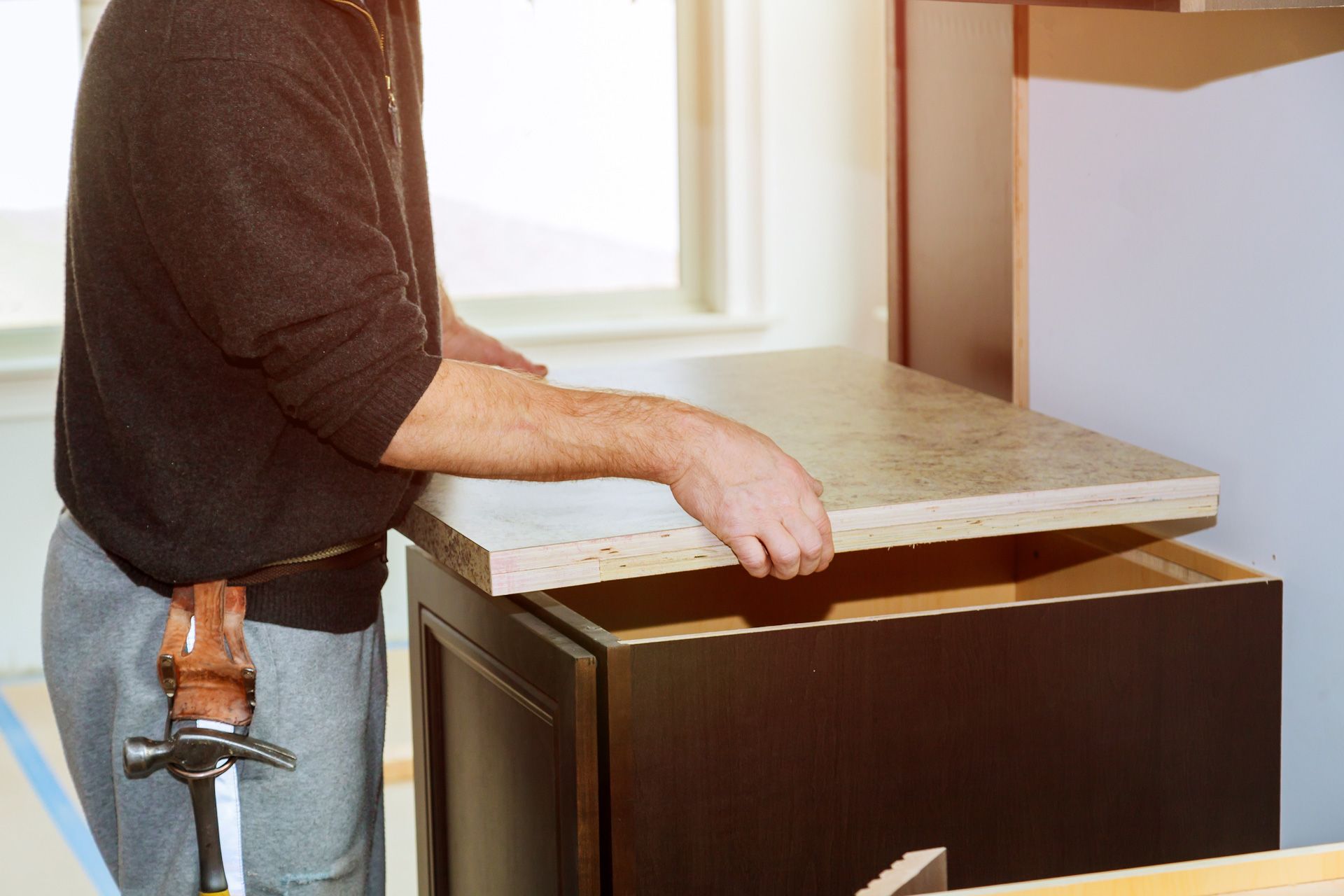 A man is installing a counter top in a kitchen.