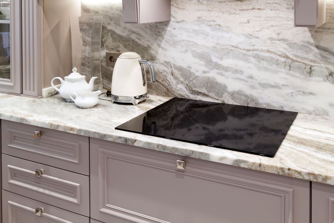 A kitchen with a stove top oven and a kettle on the counter.