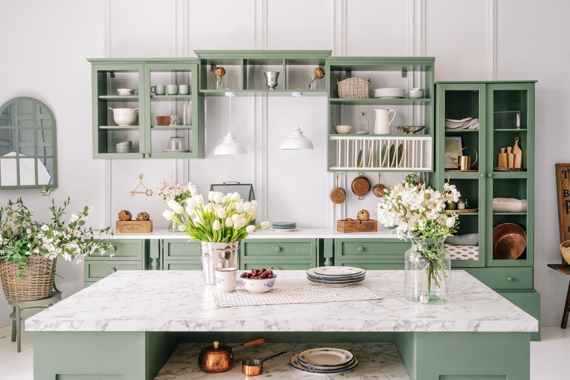 A kitchen with green cabinets and a large island with flowers on it.