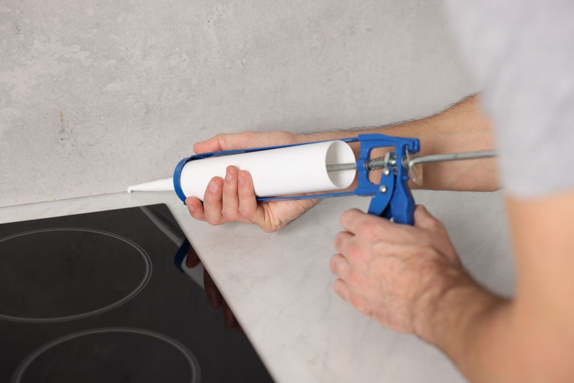 Man with caulking gun sealing countertop