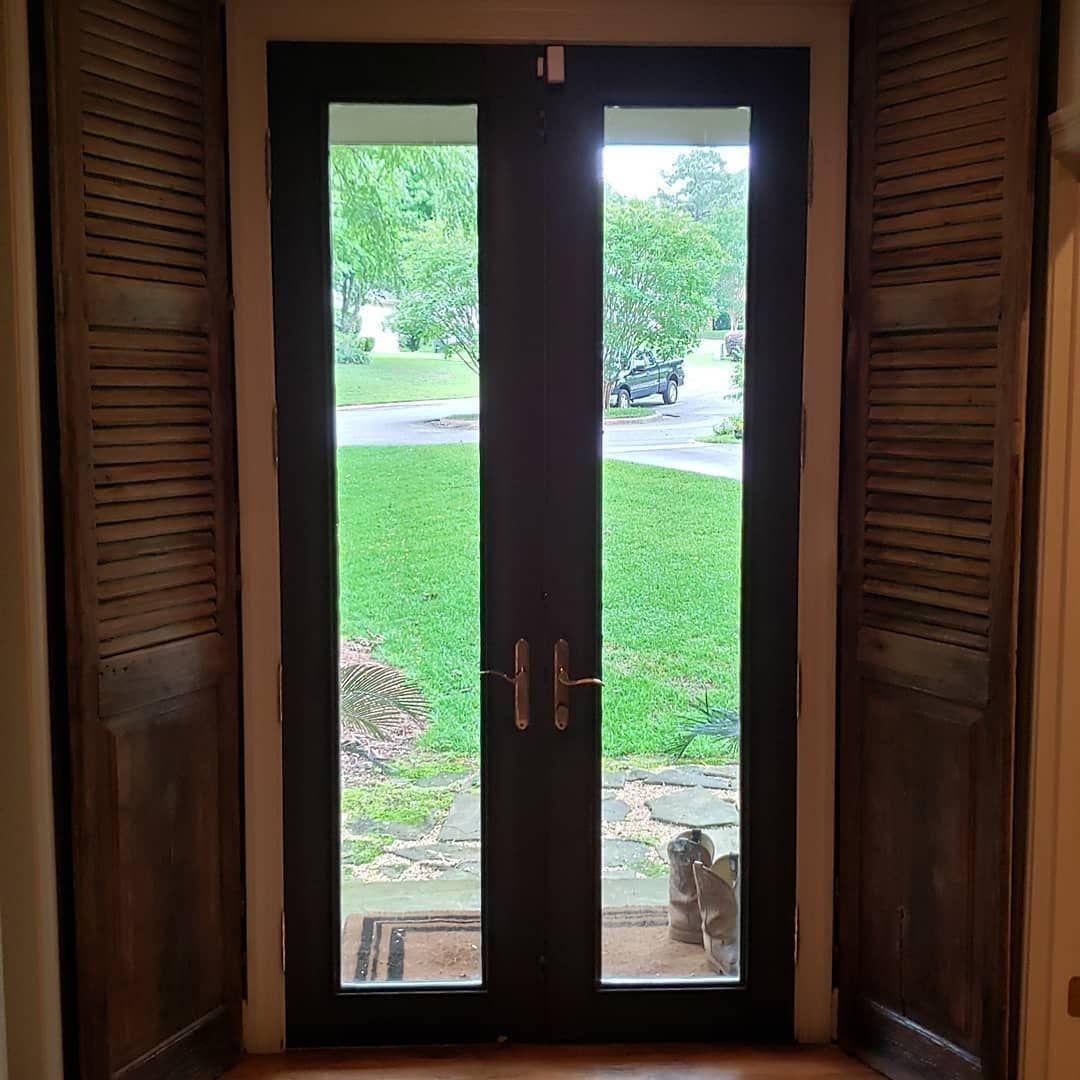 A door with shutters on it and a view of a yard.