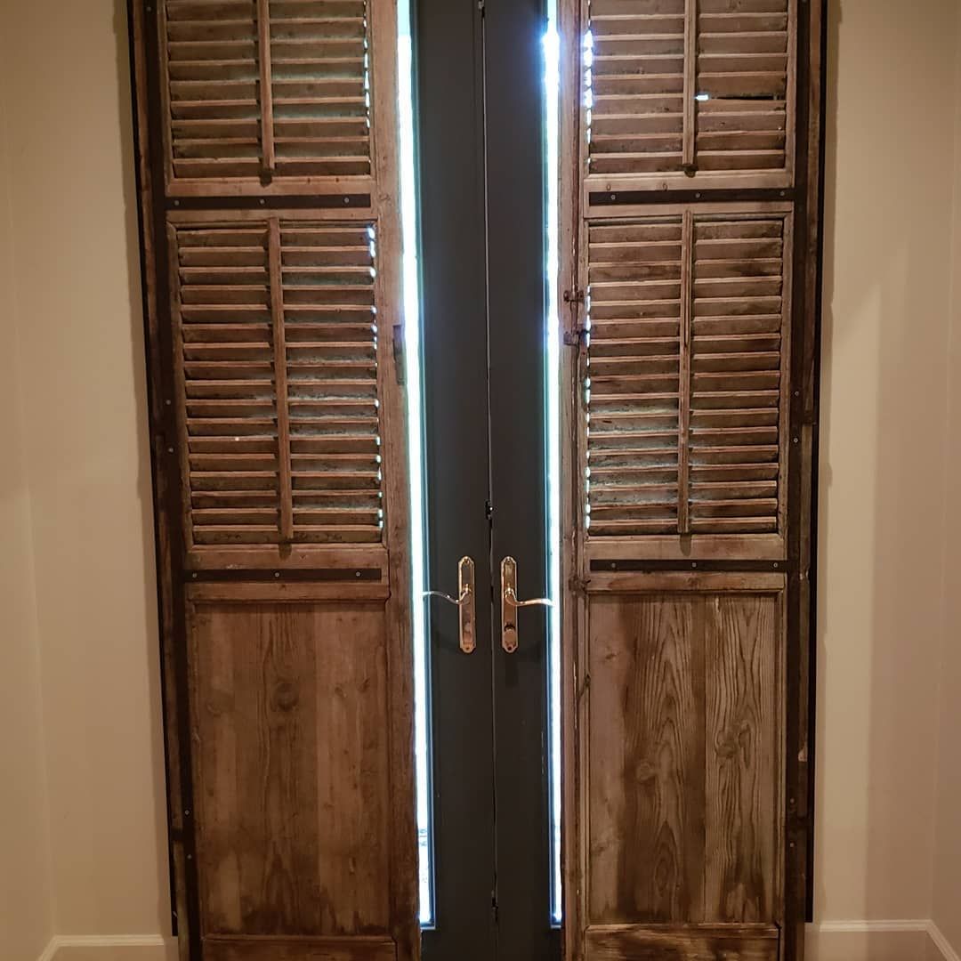 A pair of wooden shutters on a door in a room.