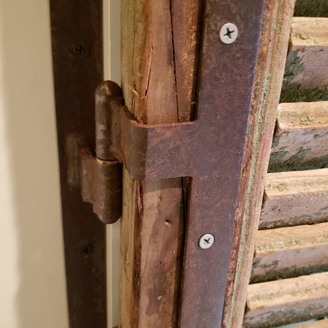 A close up of a rusty hinge on a wooden door.