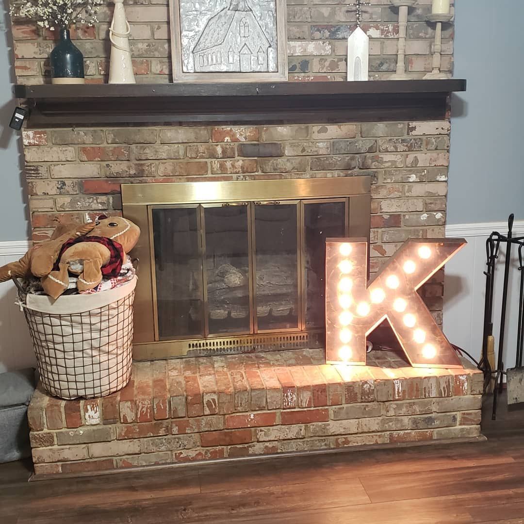 A brick fireplace with a lighted letter k on it