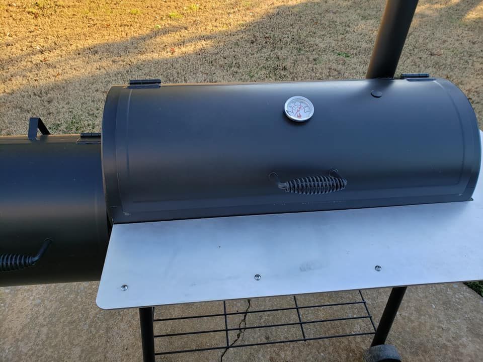 A black bbq grill with a thermometer on top of it.