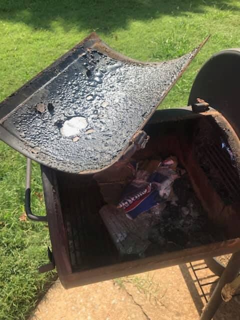 A grill with the lid open and a bag of ice in it.