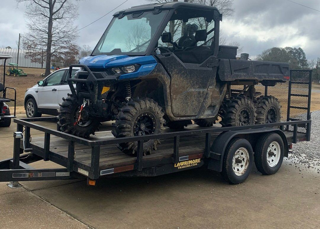 A blue atv is sitting on top of a trailer.
