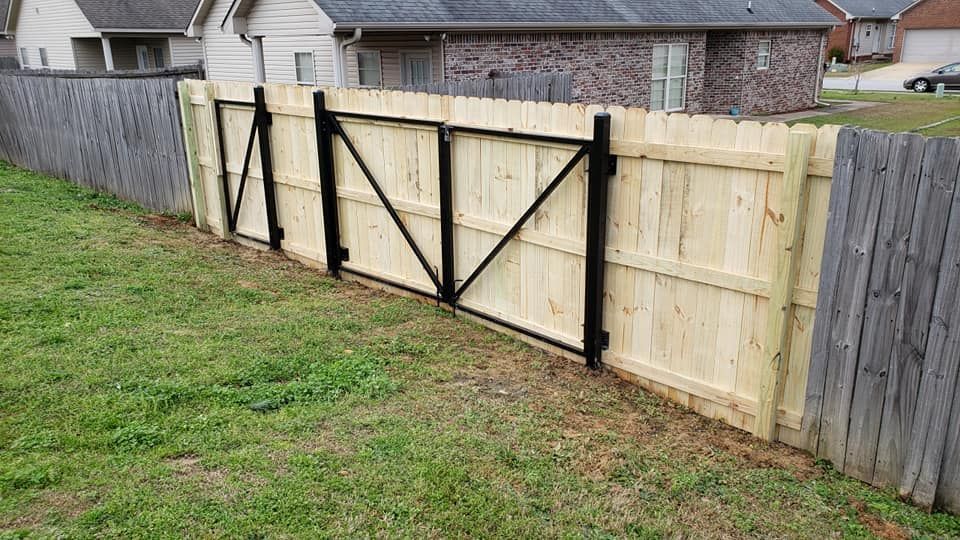 A wooden fence with a black gate in the backyard of a house.