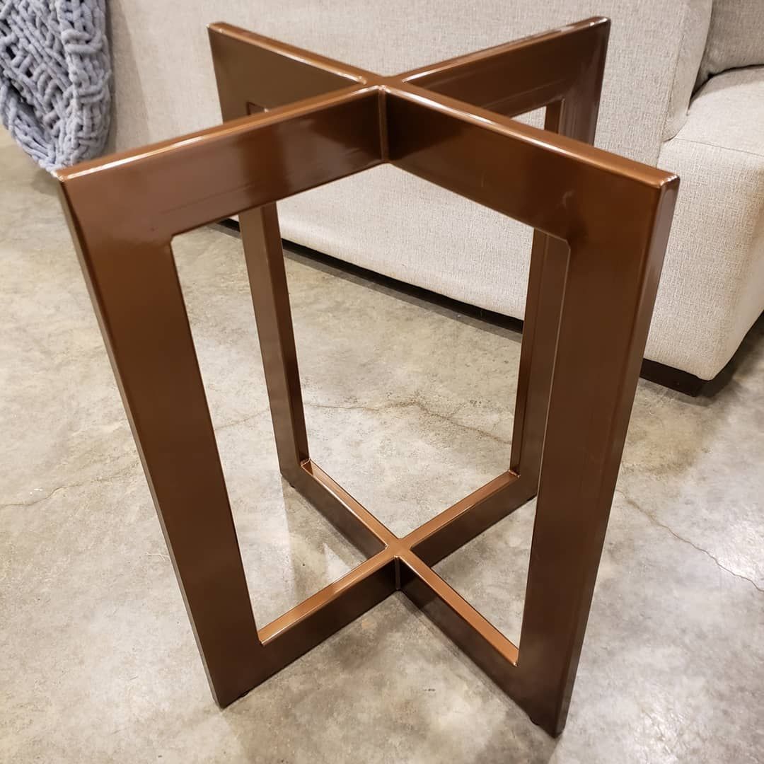 A wooden table frame is sitting on a concrete floor next to a couch.