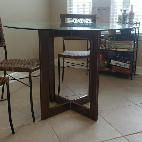 A dining room table with wicker chairs and a glass top.