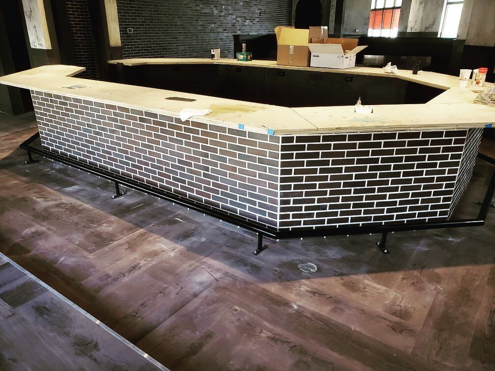 A long brick bar in a room with a wooden floor.