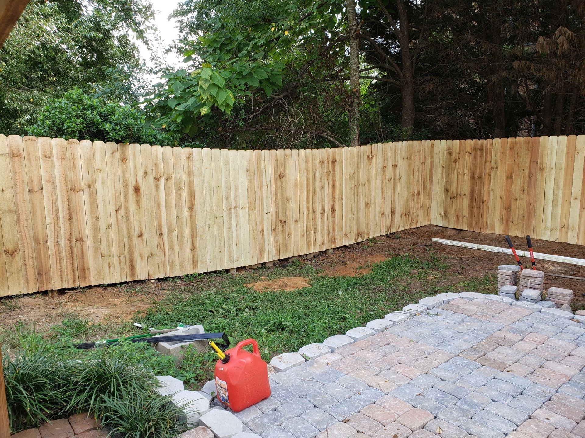 A wooden fence is being built in a backyard.