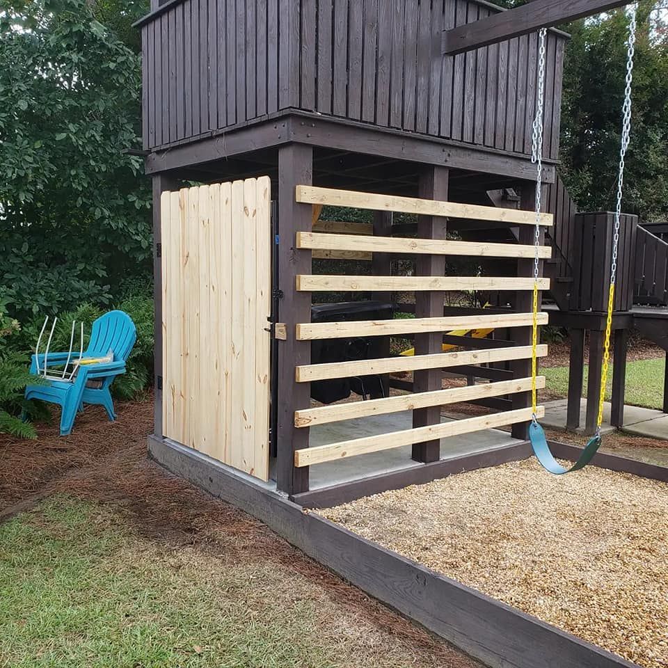 A blue chair is sitting next to a wooden fence and a swing set.