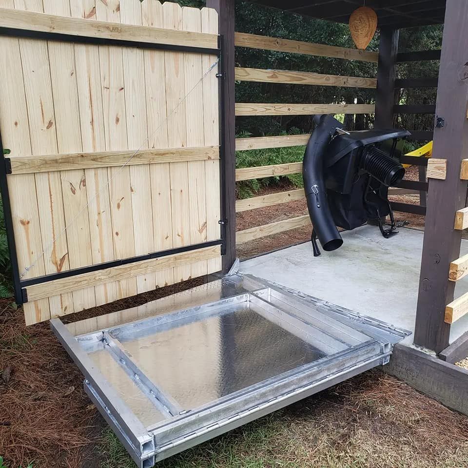 A metal tray is sitting in front of a wooden fence