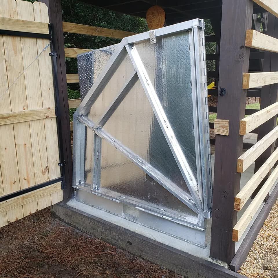 A wooden fence with a metal gate that is open
