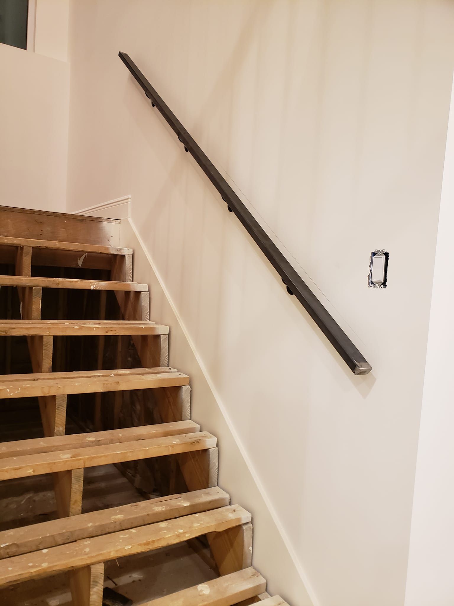 A wooden staircase with a handrail attached to the wall.