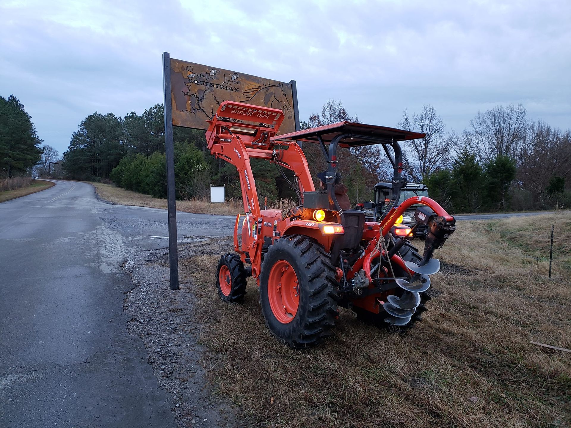 A tractor is parked on the side of the road next to a sign.