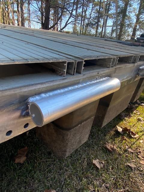 A metal bar is attached to the side of a wooden dock.