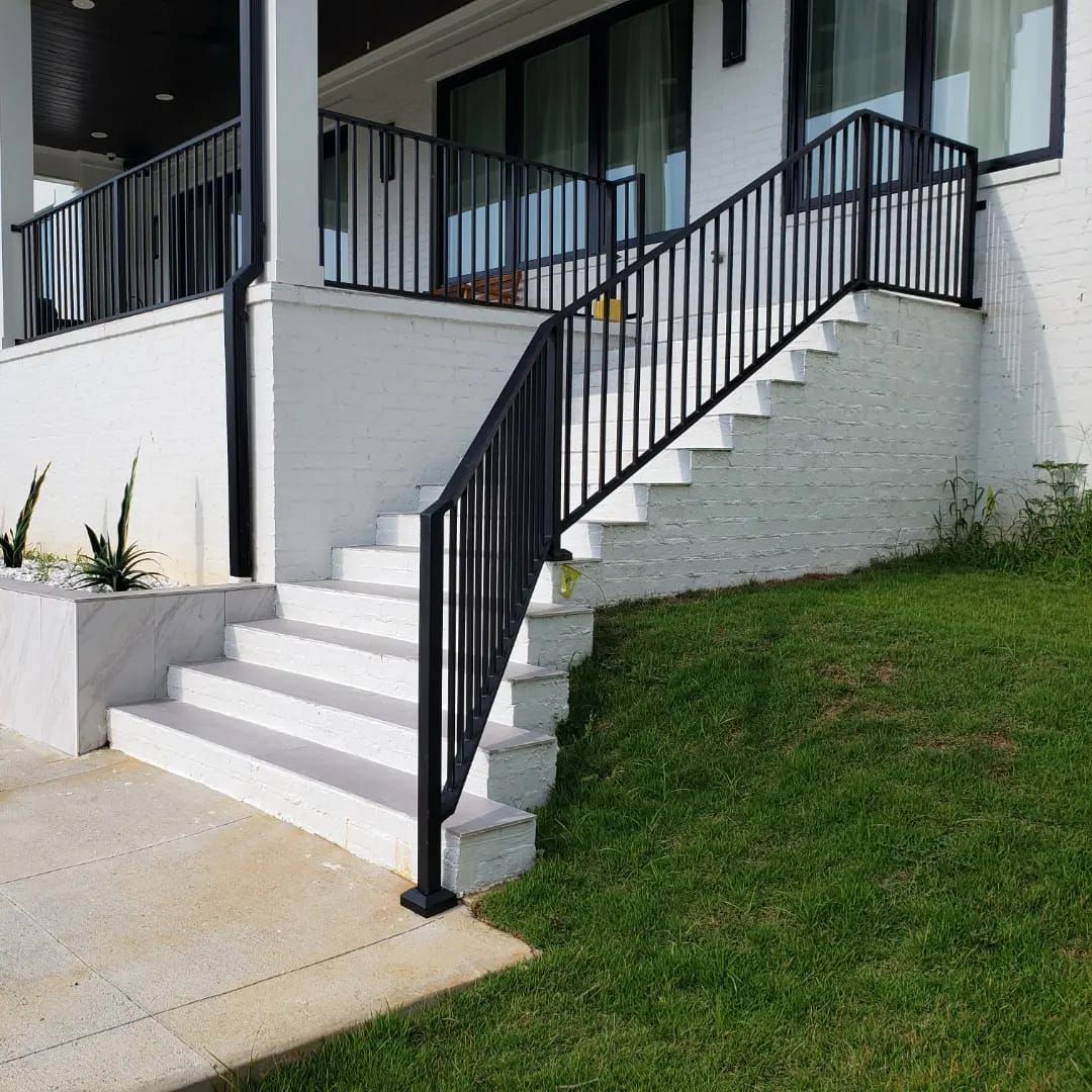 A set of stairs leading up to a white house with a black railing.