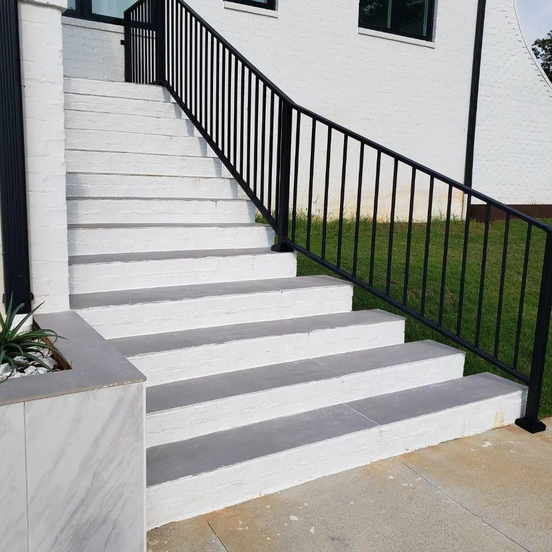 A set of stairs with a black railing leading up to a white building.