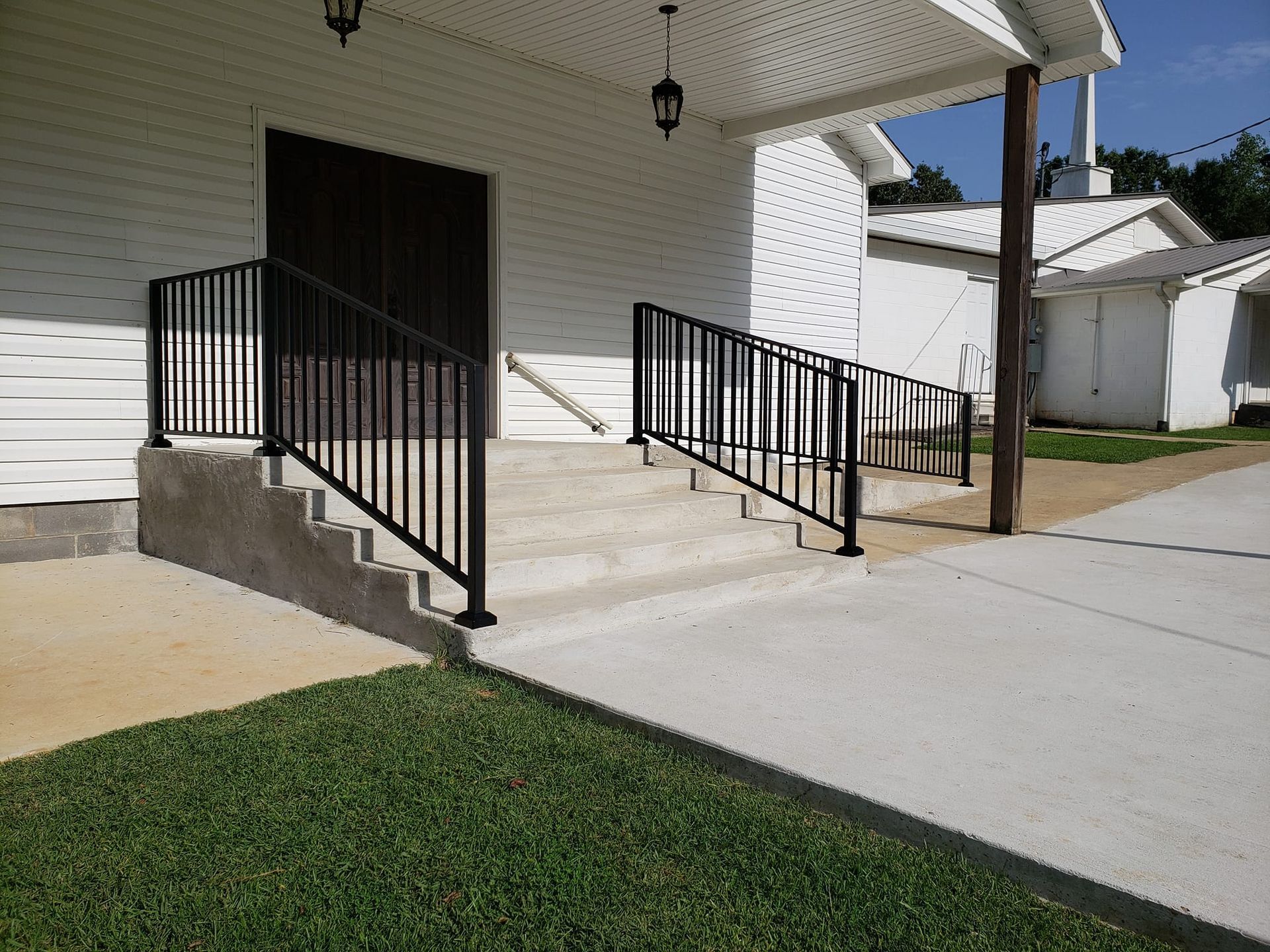A white building with a black railing and stairs leading up to it.