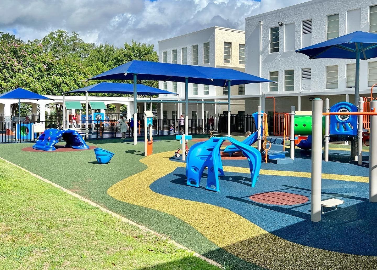 A playground with blue umbrellas in front of a building