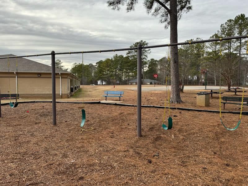 A playground with swings and a bench in the background