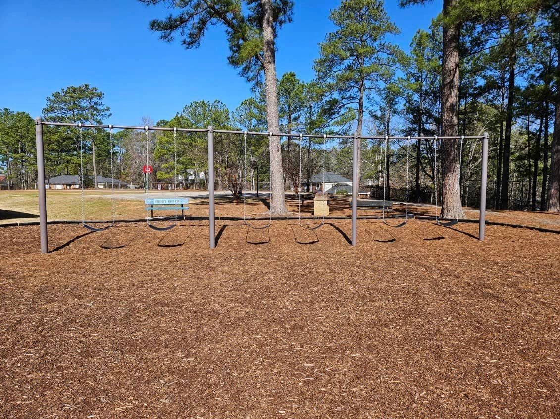 A playground with a bench and a basketball hoop in the background.