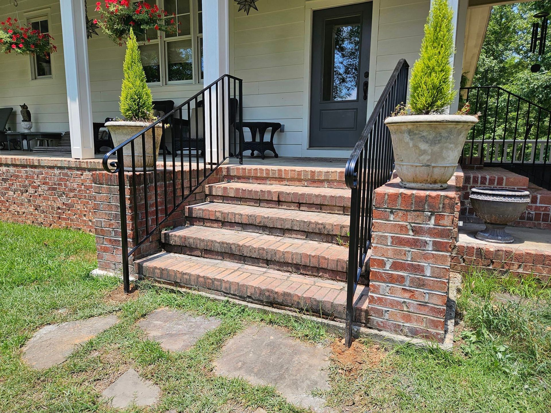 A brick porch with stairs leading up to it and a wrought iron railing.