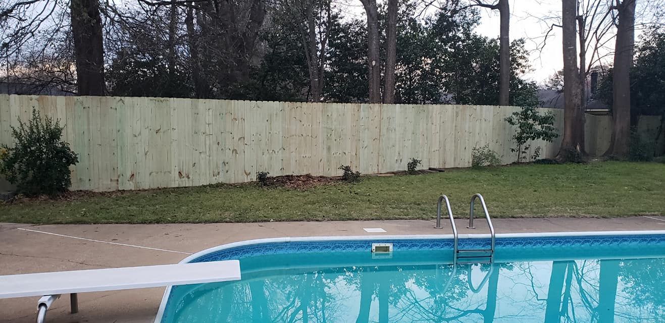 A large swimming pool with a wooden fence in the background