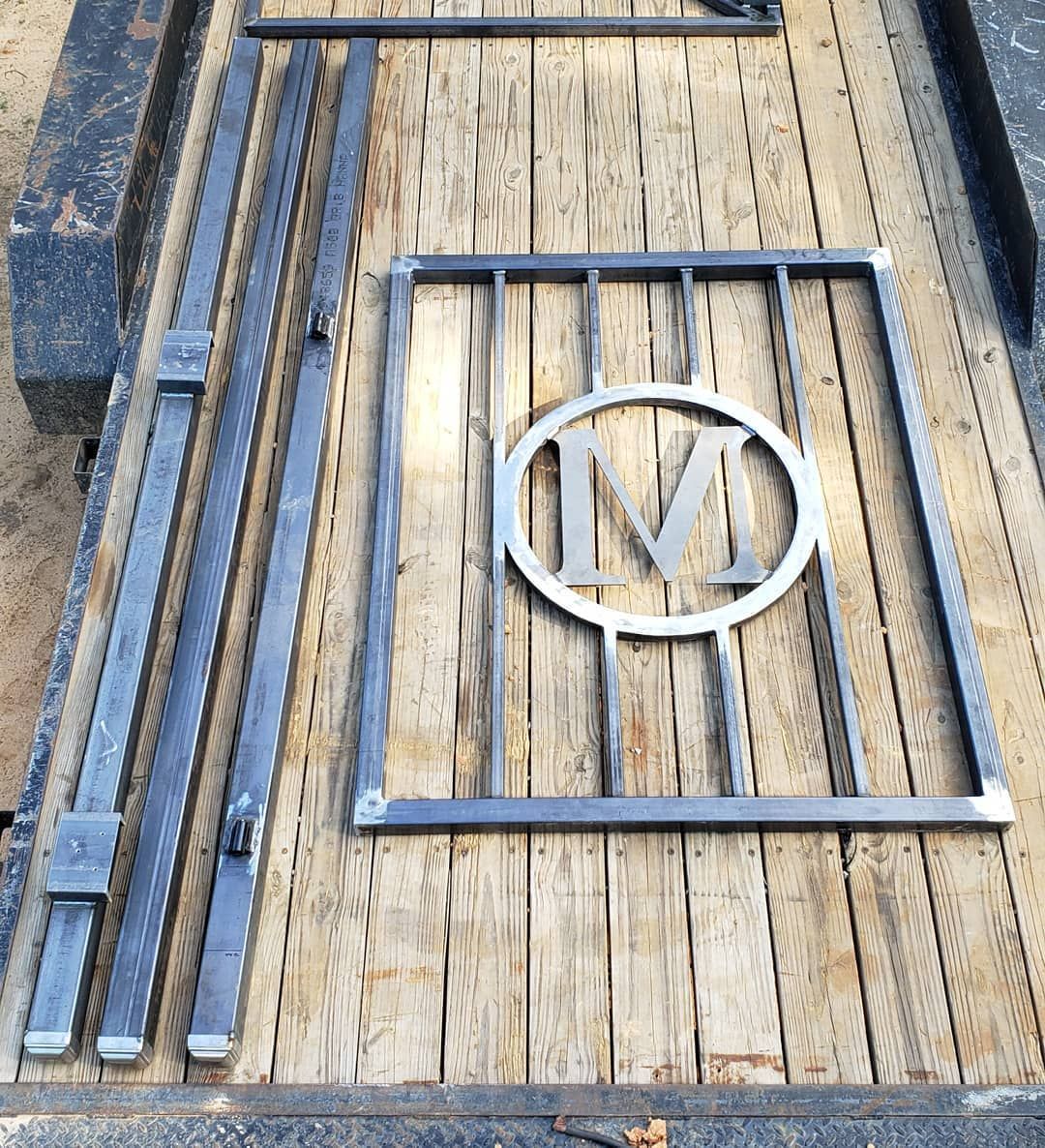 A metal gate with the letter m on it is sitting on top of a wooden table.