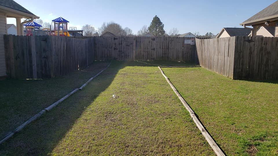 A backyard with a wooden fence and a playground in the background.