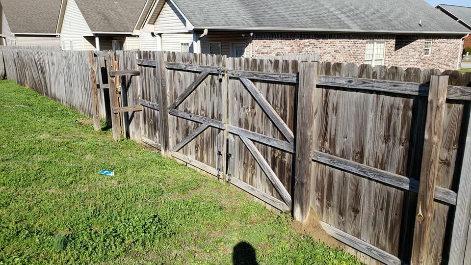 A wooden fence with a gate in the backyard of a house.