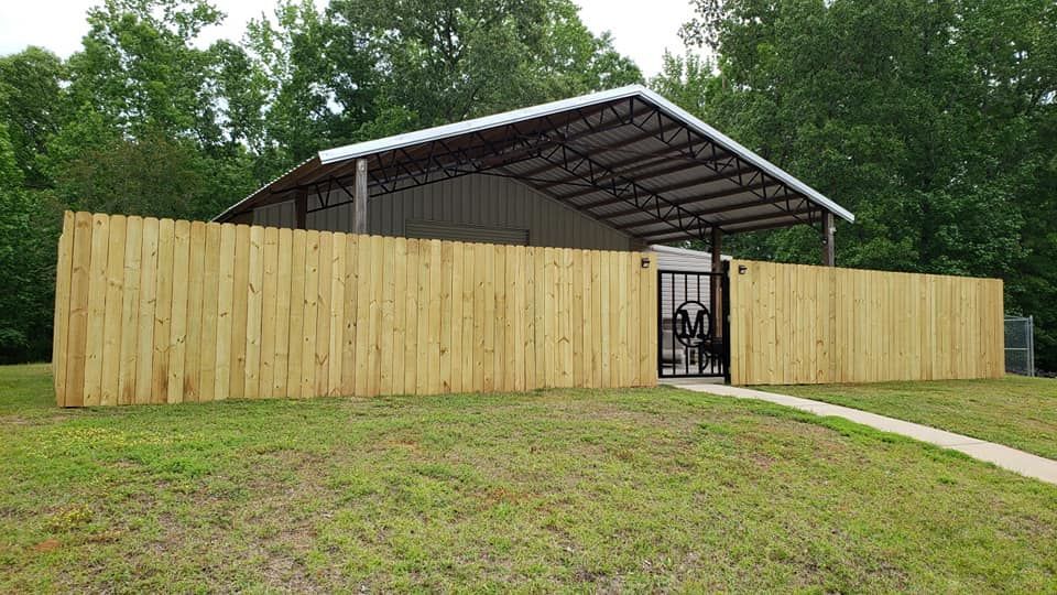 A wooden fence surrounds a building with a roof.