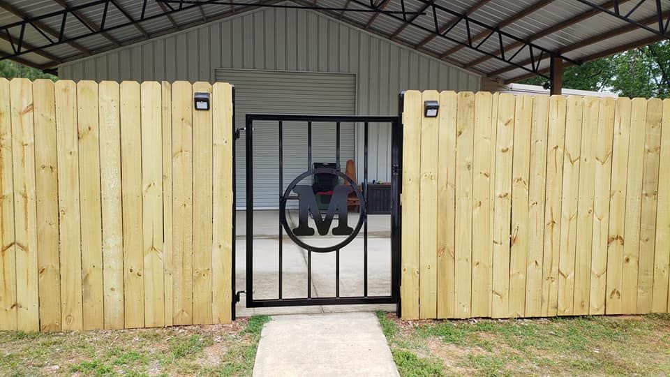 A wooden fence with a metal gate in front of a garage.