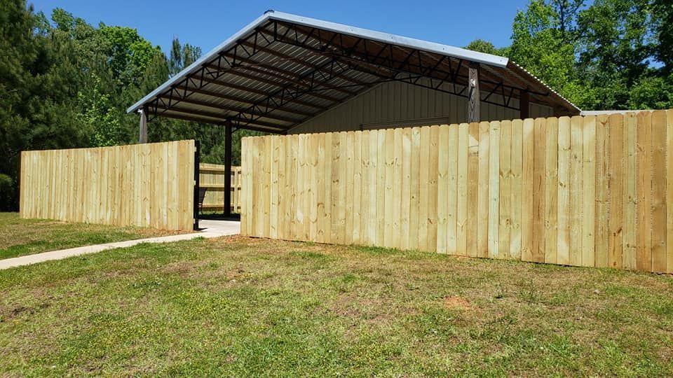 A wooden fence is surrounding a building with a roof.