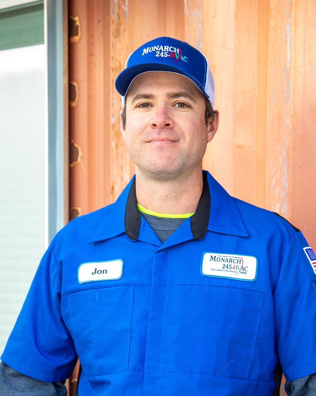 Man in blue work uniform and cap, smiling. Name tag says