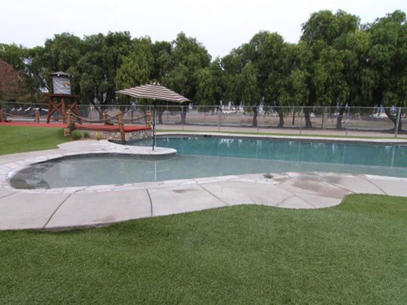 Empty outdoor swimming pool with a small spa, red railing, and trees in the background