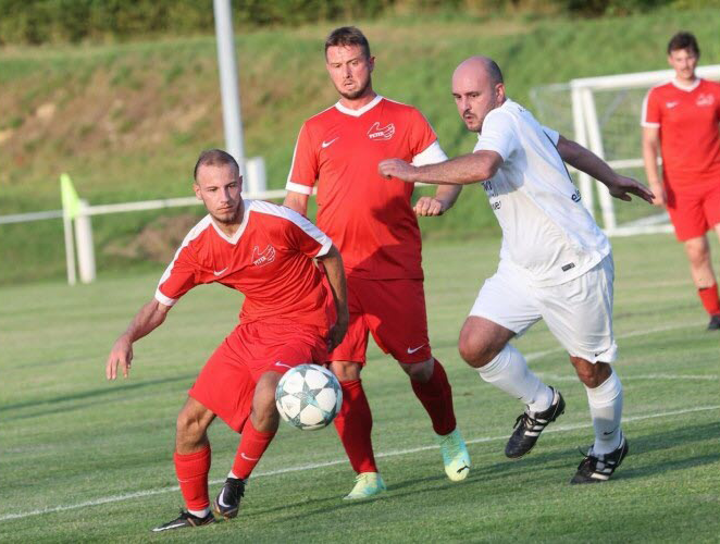 Un groupe d'hommes jouent au football sur un terrain.