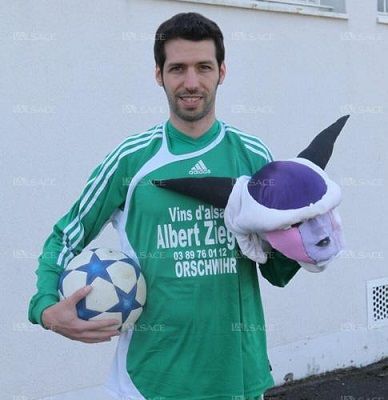 Un homme portant une chemise verte Albert Zieg tient un ballon de football et un animal en peluche