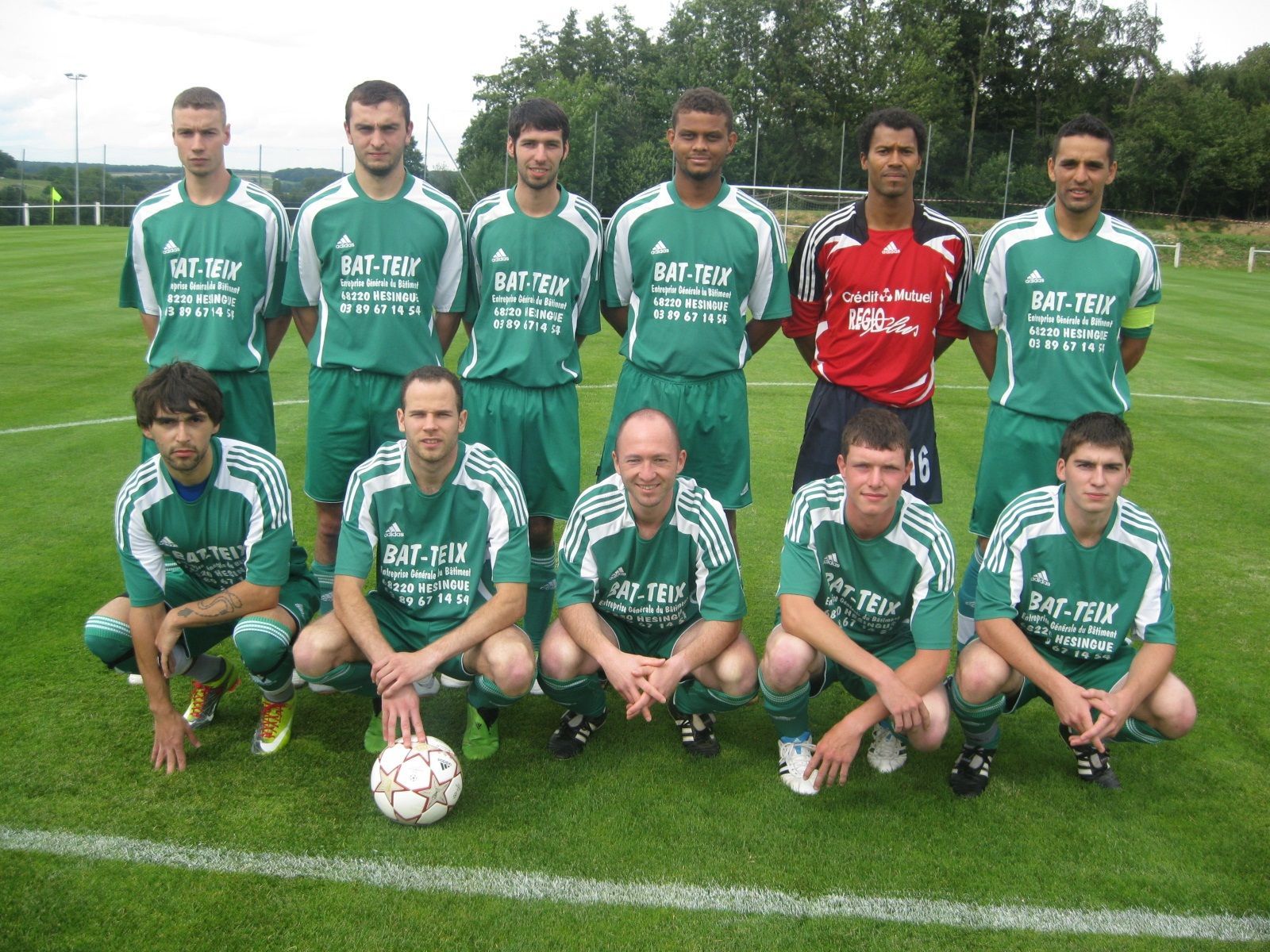 Un groupe de joueurs de football pose pour une photo et sur l'un de leurs maillots est écrit 